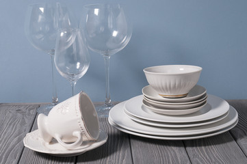 Minimalistic still life: set of rustic gray wooden tableware on blue background. Soft light, high key.