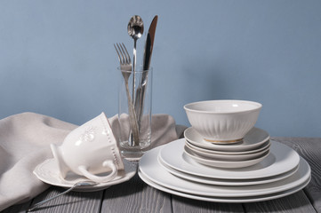 Minimalistic still life: set of rustic gray wooden tableware on blue background. Soft light, high key.