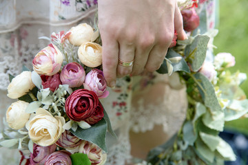 Young woman holding wreath from lily of the valley in her hands. Close up