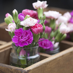 the Small bouquets of pink and white carnations in a wooden box like a restaurant decoration