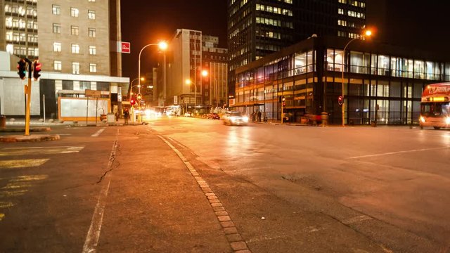 Linear timelapse moving up at a busy intersection at night with traffic and people crossing in Ghandi Square, mid city Johannesburg, South Africa