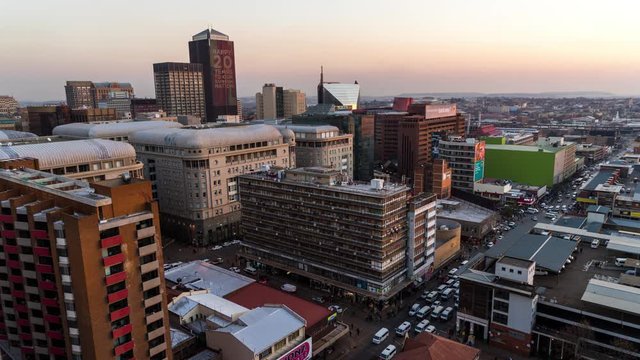 Medium timelapse at sunset/nightfall showing the view across New Town. Jeppes town and the city centre of Johannesburg during peak traffic with the hustle and bustle of people in the streets, buildings and taxis, South Africa