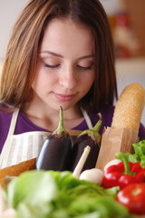 Young woman holding grocery shopping bag with vegetables Standing in the kitchen
