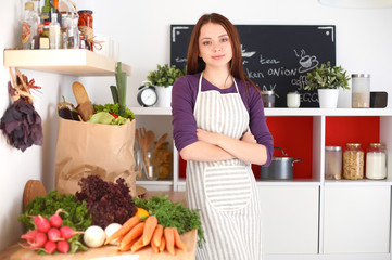 Young woman standing in her kitchen near desk