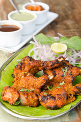 Delicious tandoori chicken starter, served with lime, onion, mint, yoghurt and sauces, on a banana leaf base.