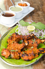 Delicious tandoori chicken starter, served with lime, onion, mint, yoghurt and sauces, on a banana leaf base.