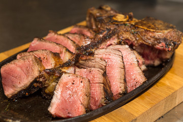 A selection of grilledT Bone steak pieces roasted garlic and rosemary, off the bone on a metal plate