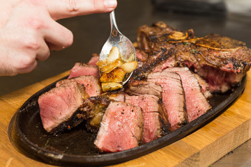 A selection of grilledT Bone steak pieces roasted garlic and rosemary, off the bone on a metal plate