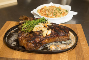 A selection of grilledT Bone steak pieces roasted garlic and rosemary, off the bone on a metal plate