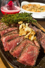 A selection of grilledT Bone steak pieces roasted garlic and rosemary, off the bone on a metal plate