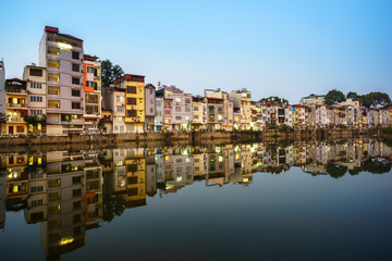 Resident houses and reflection on Tinh Bien lake in Hanoi, Vietnam