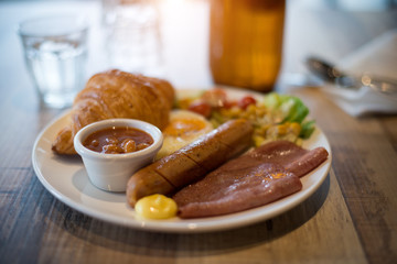 English breakfast with fried eggs, bacon, sausages, beans, toasts and fresh salad