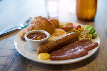 English breakfast with fried eggs, bacon, sausages, beans, toasts and fresh salad