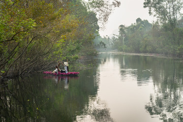 Fototapeta na wymiar River scene with a boat carrying girls wearing traditional dress Ao Dai, conical hat, and flower.