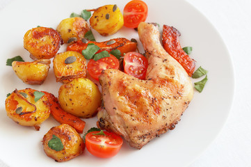 roasted chicken leg with potato, pumpkin, and cherry tomatoes decorated with cilantro and pumpkin seeds