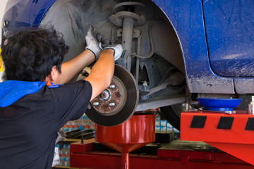 Young technician fixing brake disk in car garage