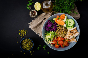 Healthy salad with chicken, tomatoes,  cucumber, lettuce, carrot, celery, red cabbage and  mung bean on dark background. Proper nutrition. Dietary menu. Flat lay. Top view