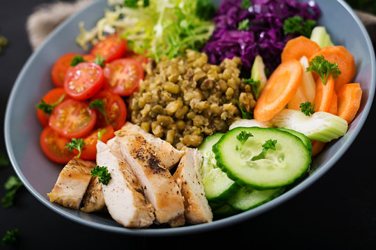 Healthy salad with chicken, tomatoes,  cucumber, lettuce, carrot, celery, red cabbage and  mung bean on dark background. Proper nutrition. Dietary menu.