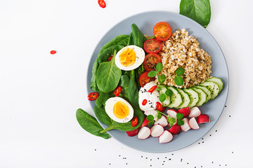 Diet menu. Healthy salad of fresh vegetables - tomatoes, cucumber, radish, egg, spinach and oatmeal on bowl. Flat lay. Top view