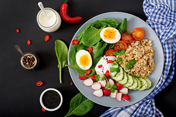 Diet menu. Healthy salad of fresh vegetables - tomatoes, cucumber, radish, egg, spinach and oatmeal on bowl. Flat lay. Top view