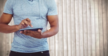 Man mid section with tablet against blurry wood panel