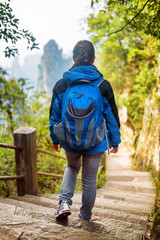 Young female tourist with blue backpack descending stairs