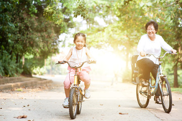 Grandmother and granddaughter biking outdoor.