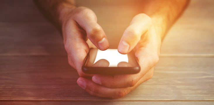 Person holding smartphone at wooden desk