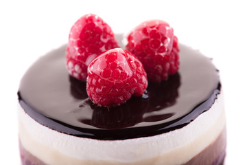 Close up of sweet and tasty chocolate cake with the raspberry on the white background.