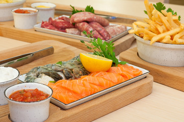 Barbecue - Salmon and Prawns - Sausages and Raw Meat in Background