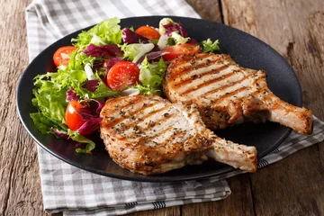 Zelfklevend Fotobehang Grilled pork steak with bone, fresh vegetable salad close-up. Horizontal © FomaA