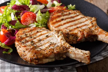 Foto auf Glas Grilled pork steak with bone and fresh salad close-up. horizontal © FomaA