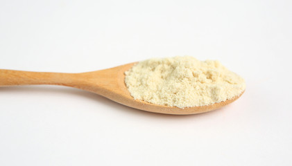 Full Powdered milk in wooden spoon over white background
