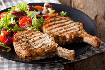 Grilled spicy pork cutlet and fresh salad close-up on a plate. horizontal