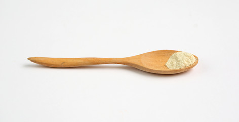 Little powdered milk in wooden spoon over white background