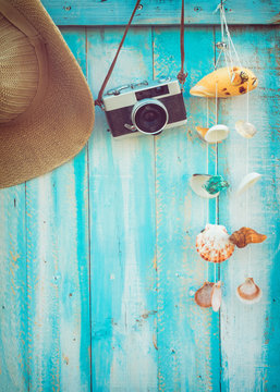 Summer background - The concept of leisure travel in the summer on a tropical beach seaside. retro camera with shell decoration hanging on wood wall background.  vintage color tone styles.
