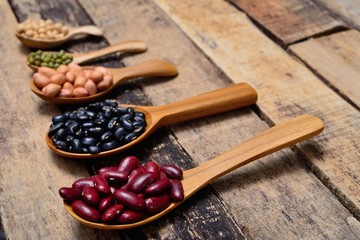 Bean seeds in wooden spoon on vintage style wooden background.