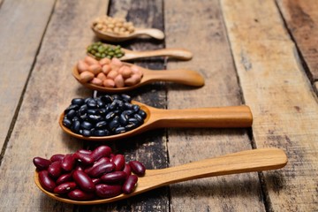 Bean seeds in wooden spoon on vintage style wooden background.