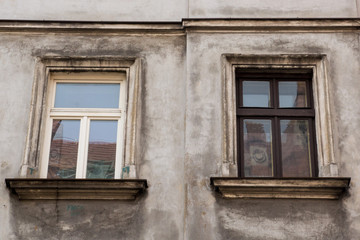 Fototapeta na wymiar Two windows on the facade of the greyj old house