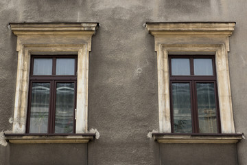 Fototapeta na wymiar Two windows on the facade of the greyj old house