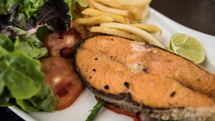 Salmon steak, fried potato chip and fresh vegetables.
