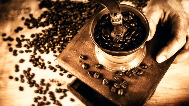 Barista grinding roasted coffee beans in old grinder mill, 4k