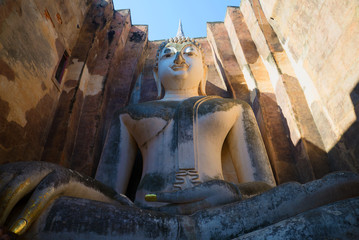 Giant sculpture of a seated Buddha on the ruins of the ancient Buddhist temple of Wat Si Chum. Sukhothai, Thailand