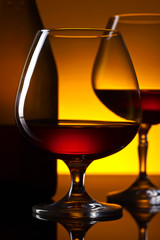  glasses of brandy and bottle on the reflective background