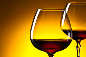 Two glasses of brandy on yellow background