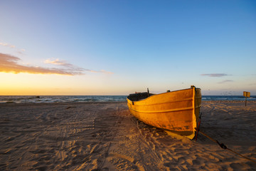 Sunset over the sea, fishing boat on the beach