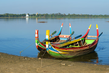 Two colored traditional Burmese boats on the shore of Taung Tha Man lake. Amarapura, Myanmar