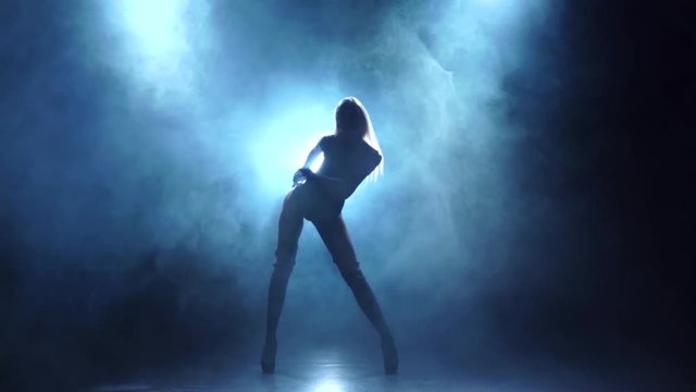 Seminude girl dancer in leather lingerie. Smoky background, slow motion