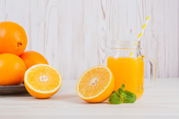 Fresh orange juice in a mason jar and orange sliced ripe on wooden table. Healthy eating concept.