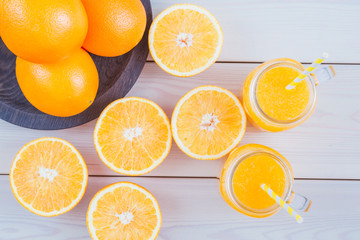Fresh orange juice in a mason jar and orange sliced ripe on wooden table. Healthy eating concept. View from above.